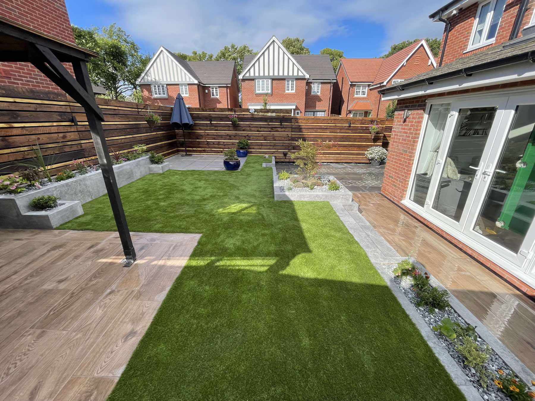 Artificial lawn, raised planters and a wood-effect patio