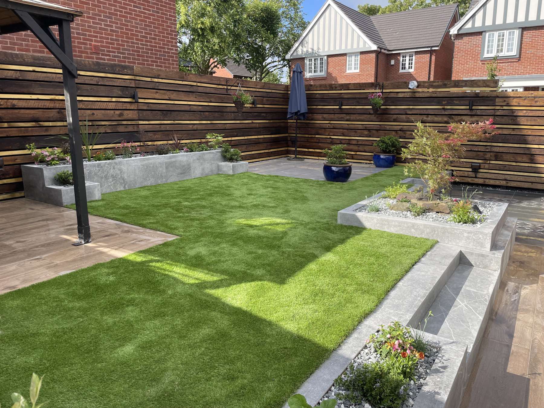 Artificial lawn with raised planters and horizontal fencing