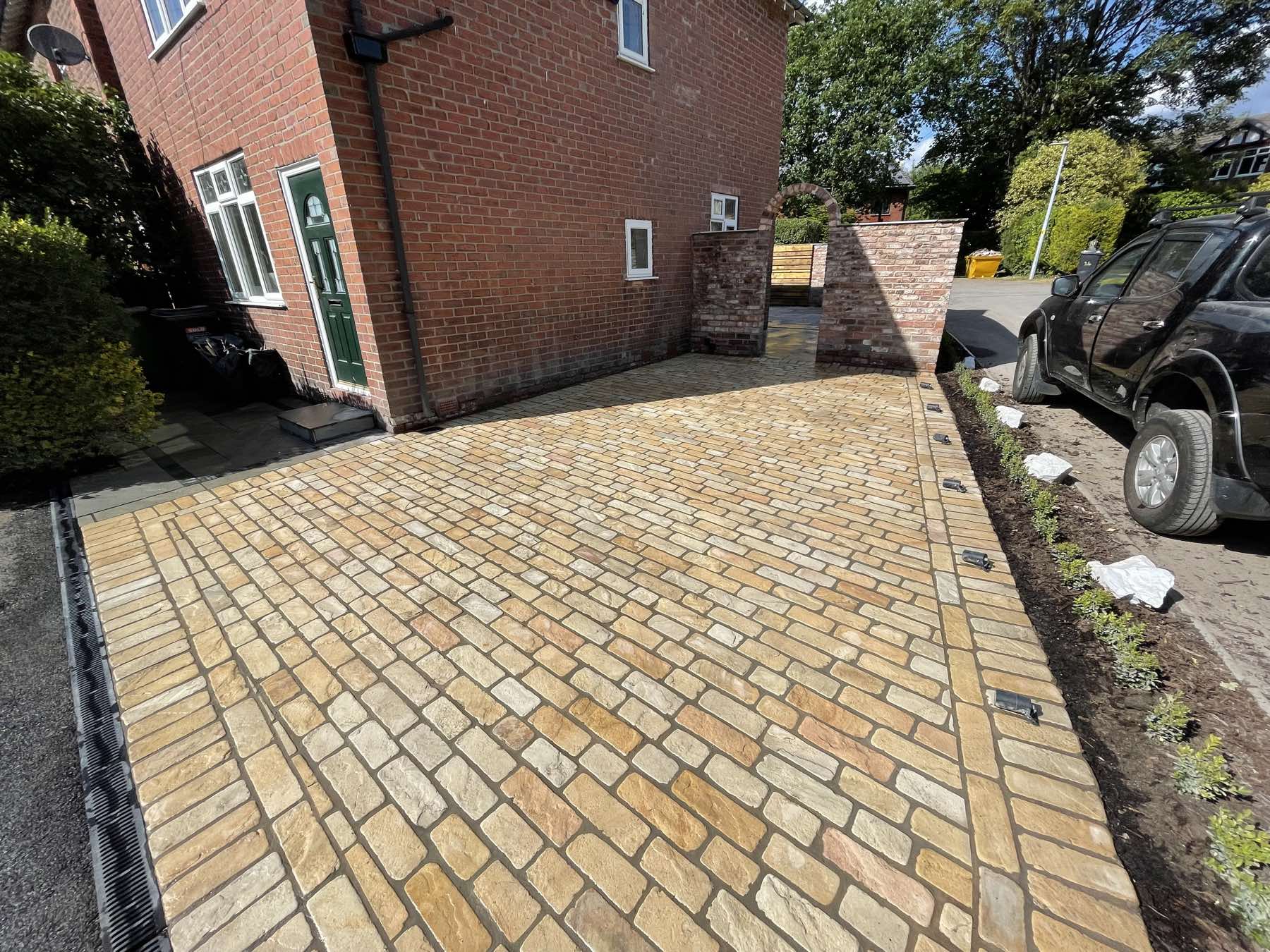 Buff block paving driveway beside a brick house
