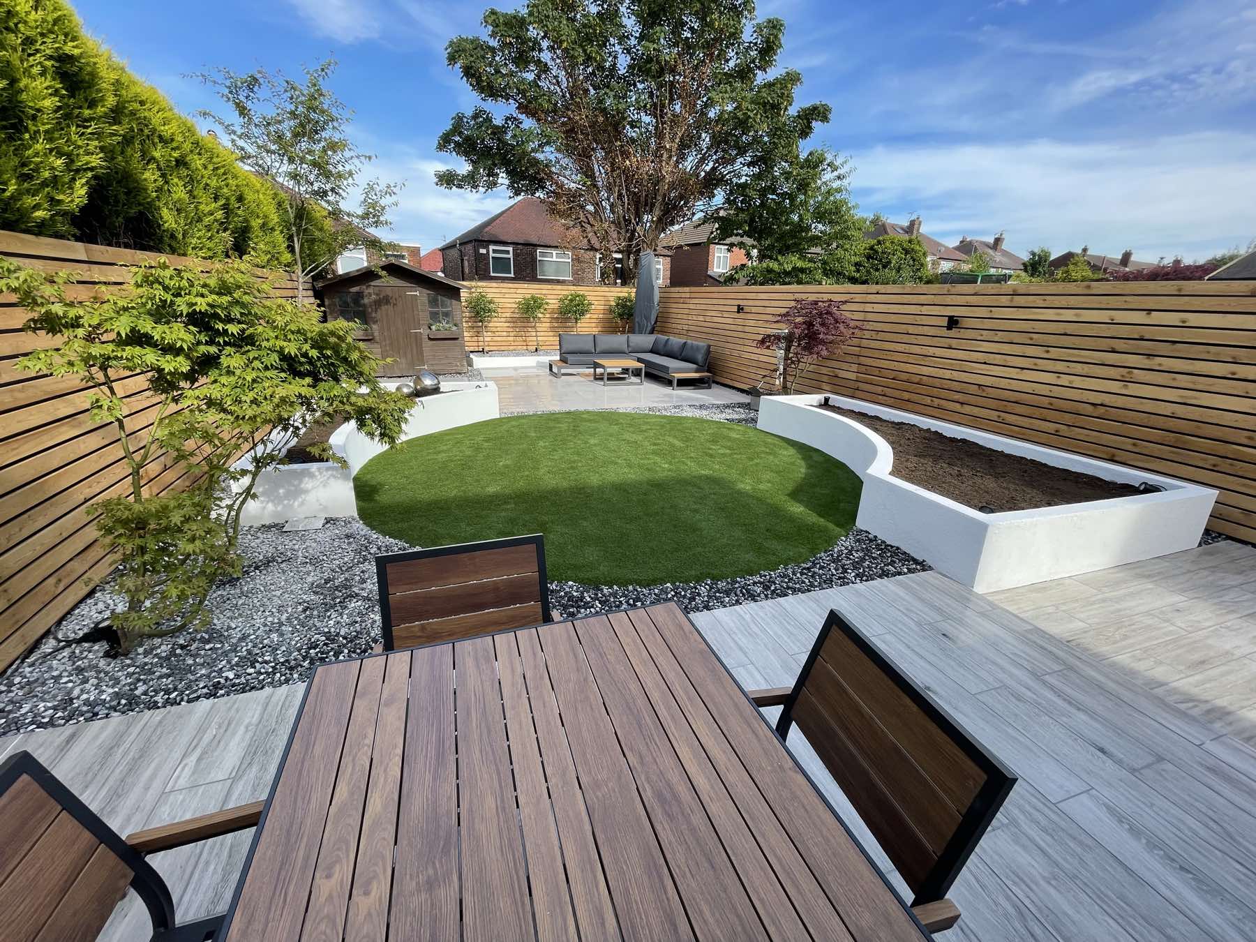 Circular lawn framed by gravel, planters and decking