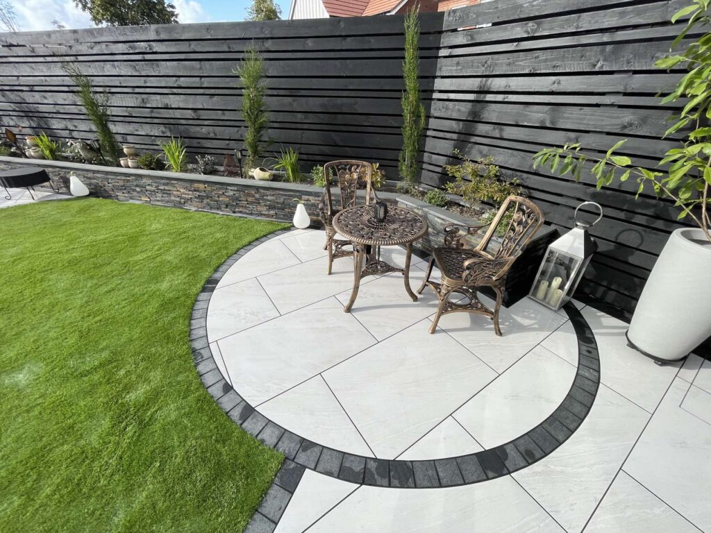 Circular porcelain patio with a dark border beside a lawn