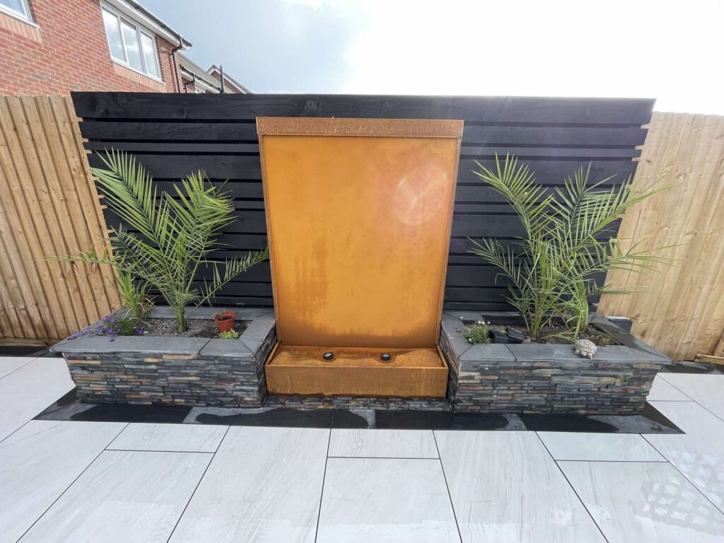 Corten steel water feature with planters and palms