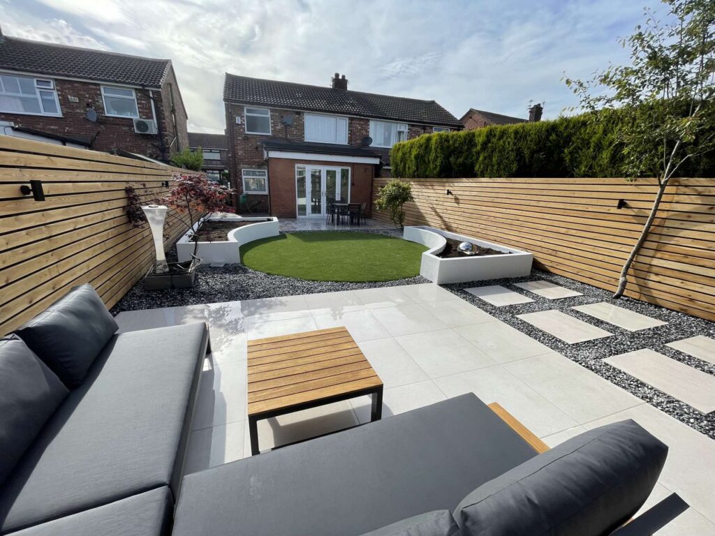 Garden with a circular lawn, white raised planters and outdoor sofa