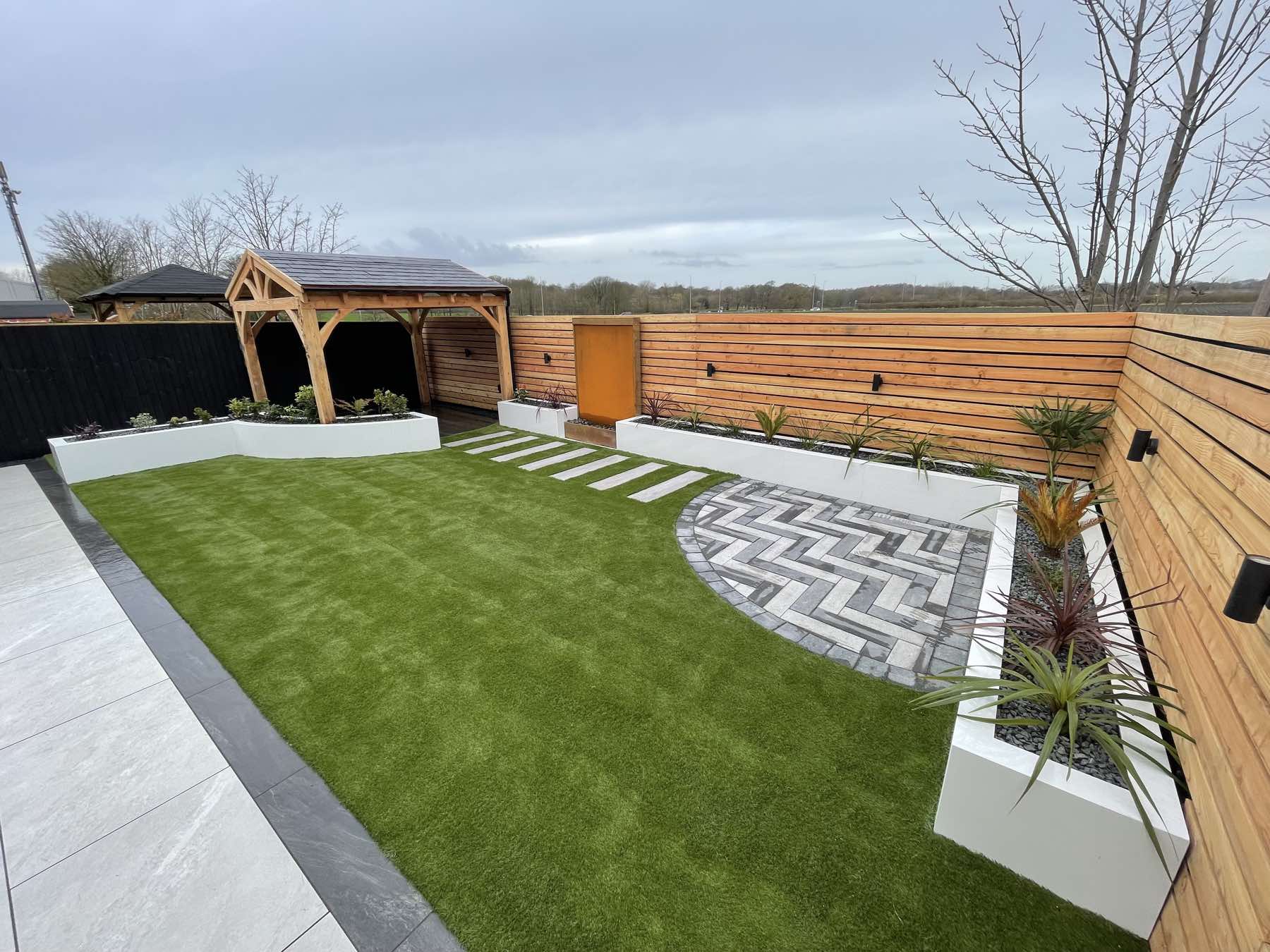 Landscaped garden with an oak gazebo, raised planters and herringbone paving