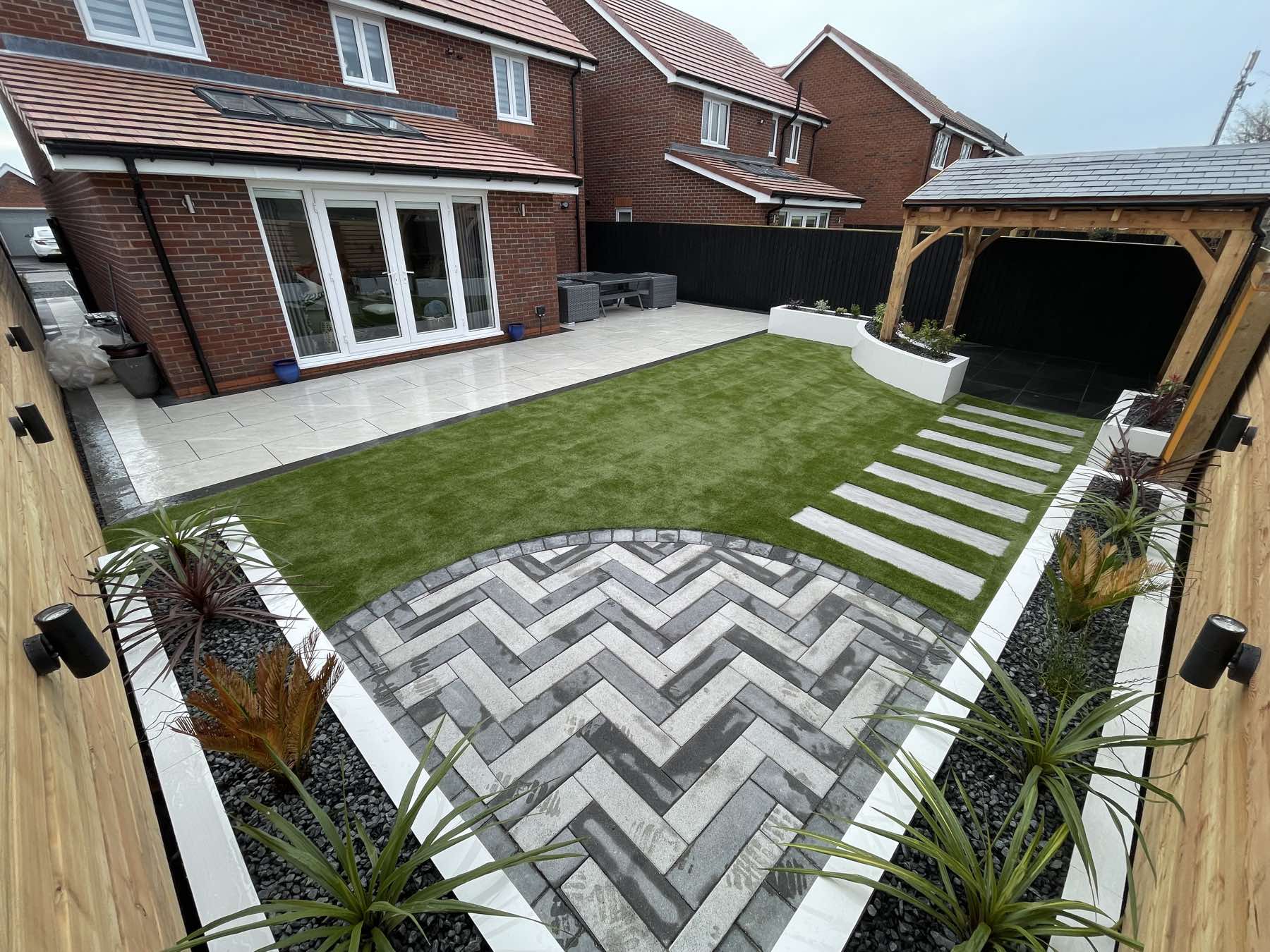 Herringbone block paving and artificial lawn with an oak pergola
