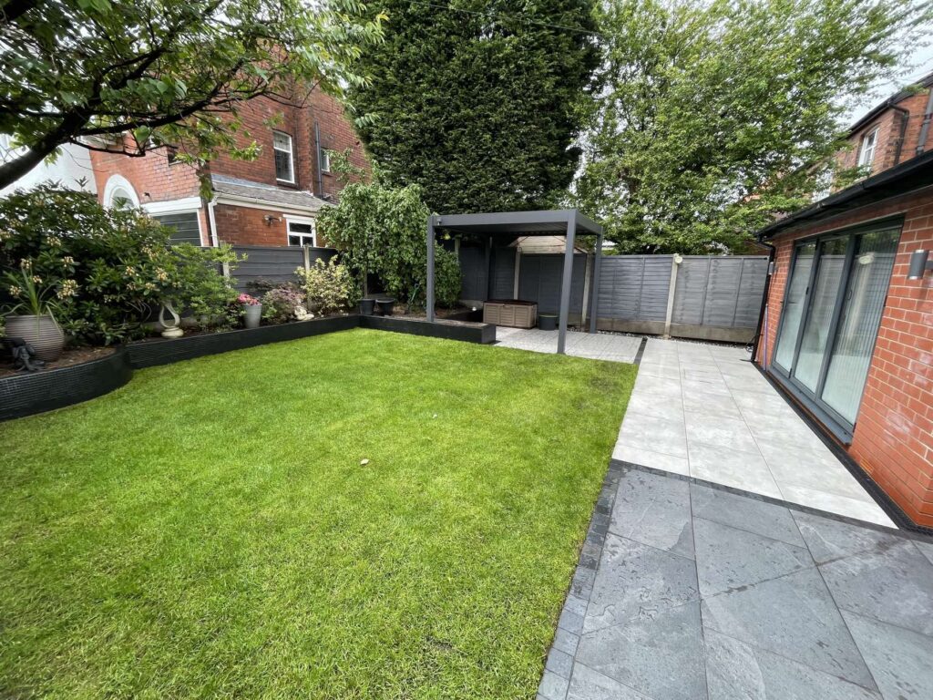 Lawn with a dark slate patio and aluminium pergola