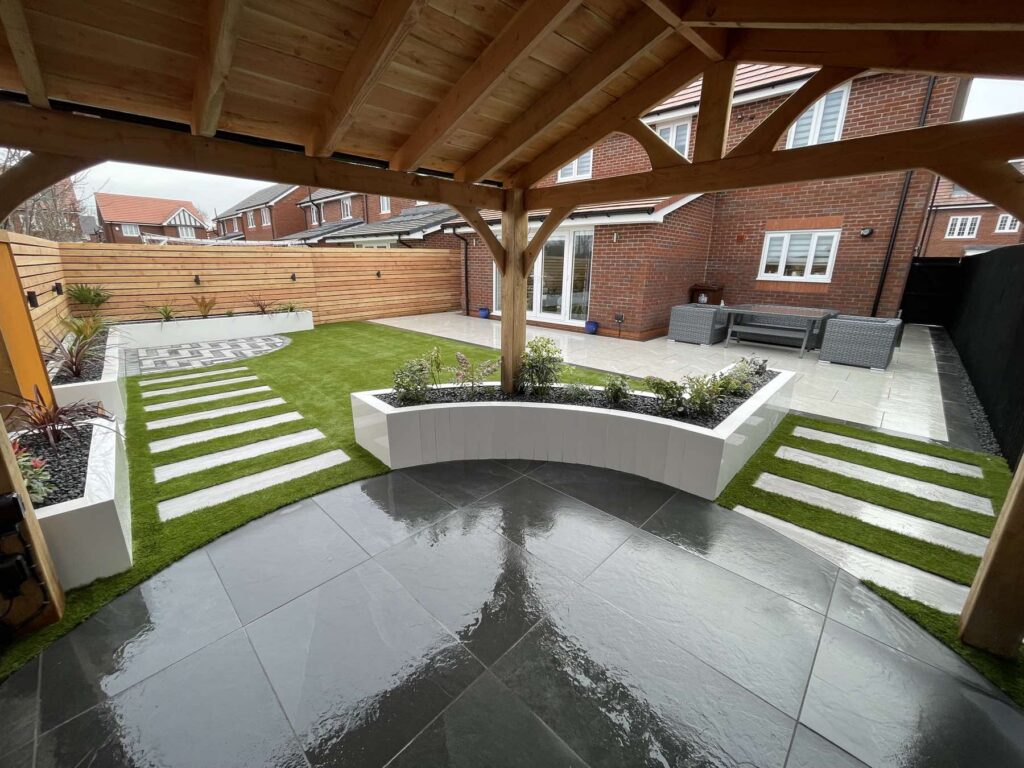 Oak pergola with white raised planters, stepping stones and porcelain patio