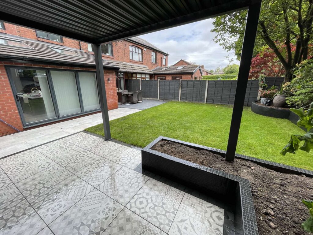 View from under a pergola across patterned tiles to the lawn