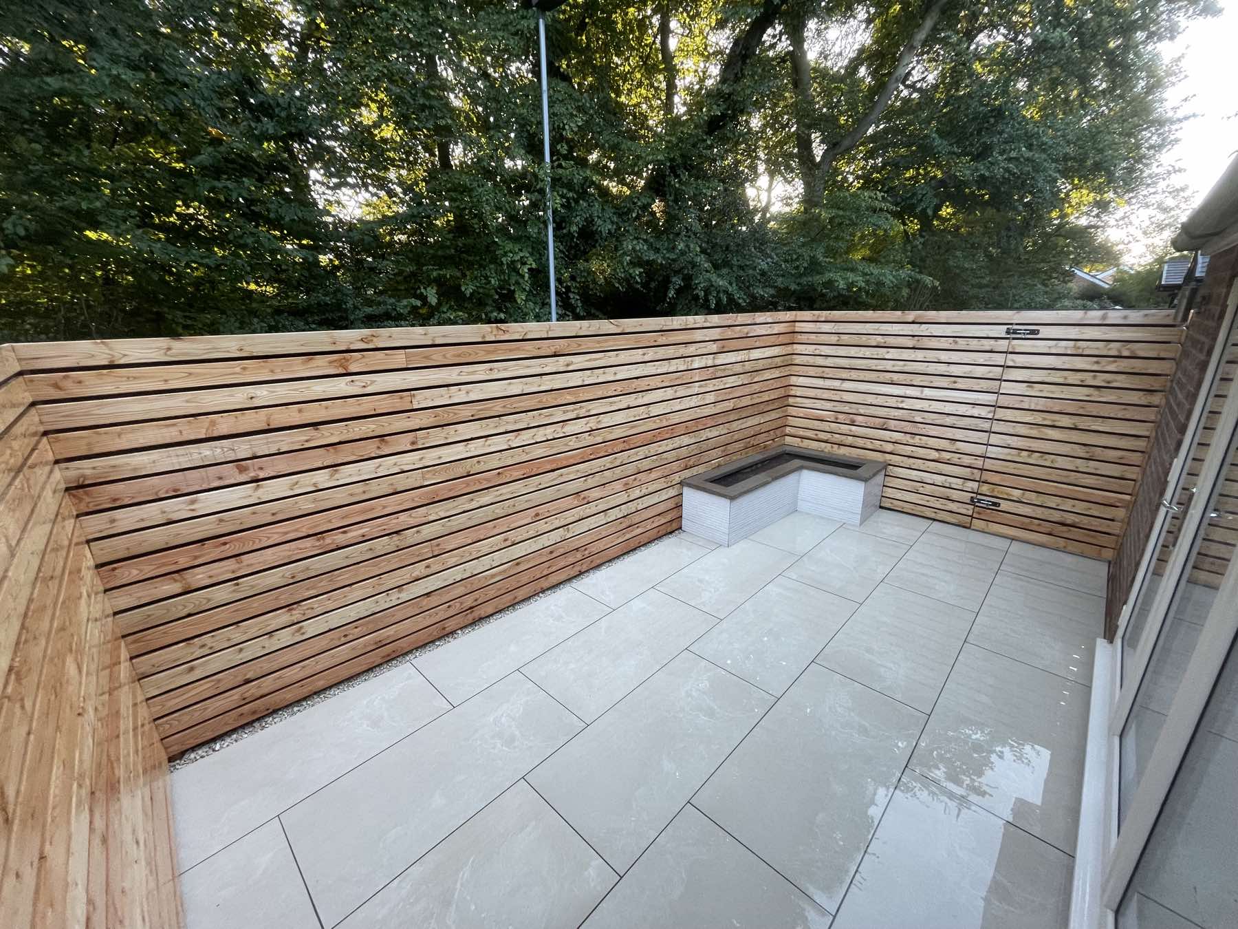 Porcelain courtyard enclosed by a slatted timber fence
