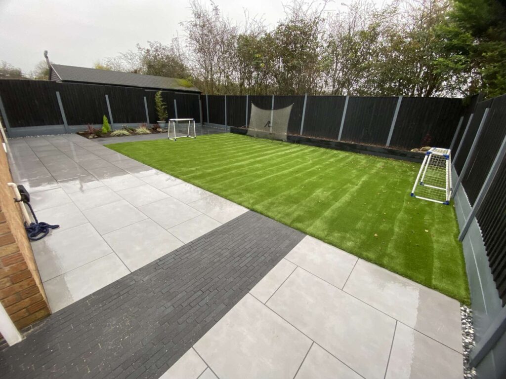 Porcelain patio with a dark paving strip and artificial lawn