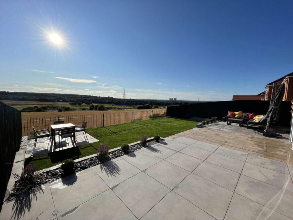 Sunny porcelain patio and lawn overlooking open countryside