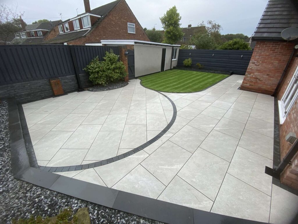 Porcelain patio with a curved dark border leading to a lawn