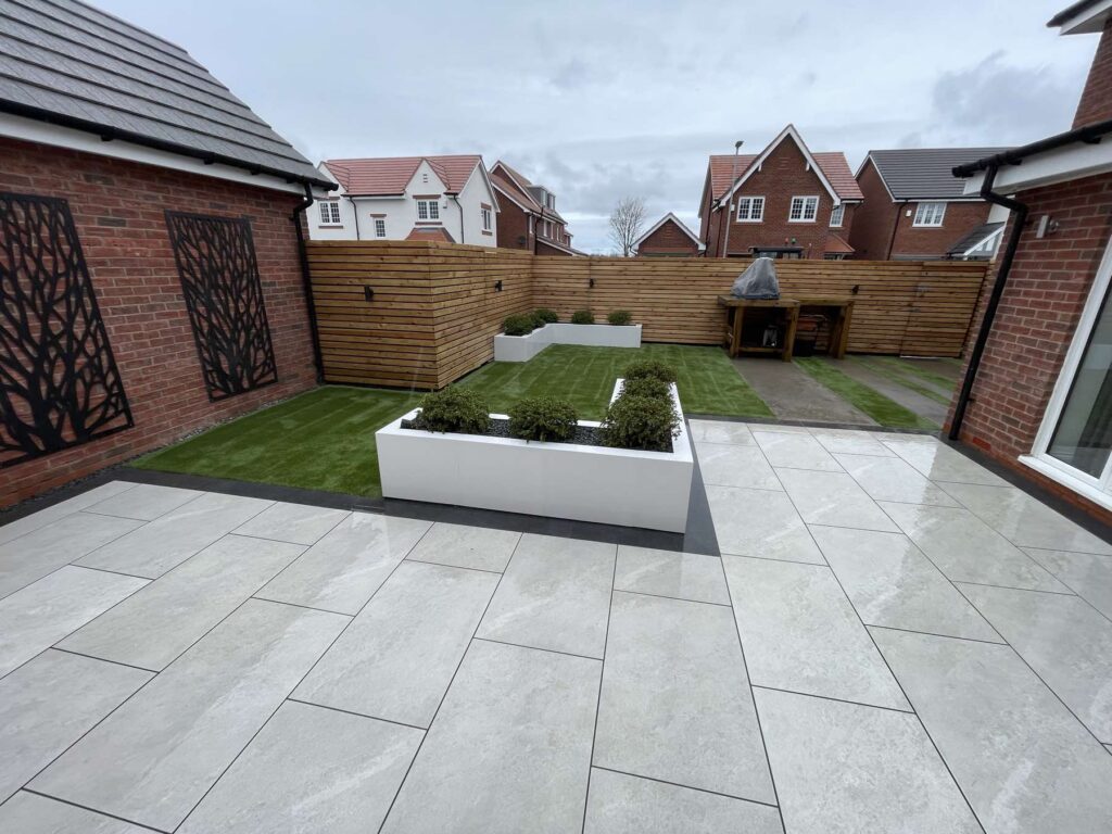 Light porcelain patio with a white planter and lawn