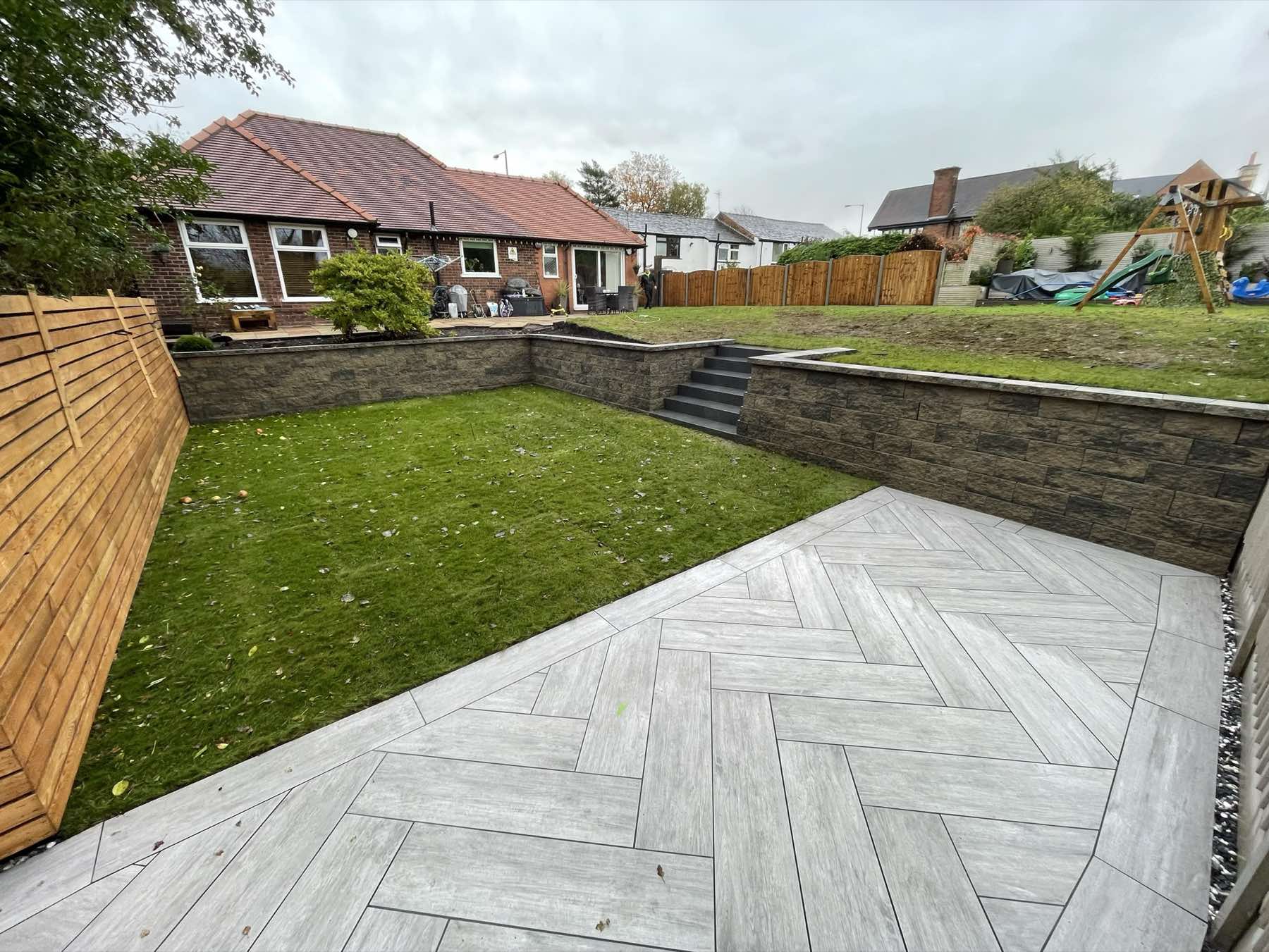 Wood-effect porcelain patio and lawn with block retaining wall